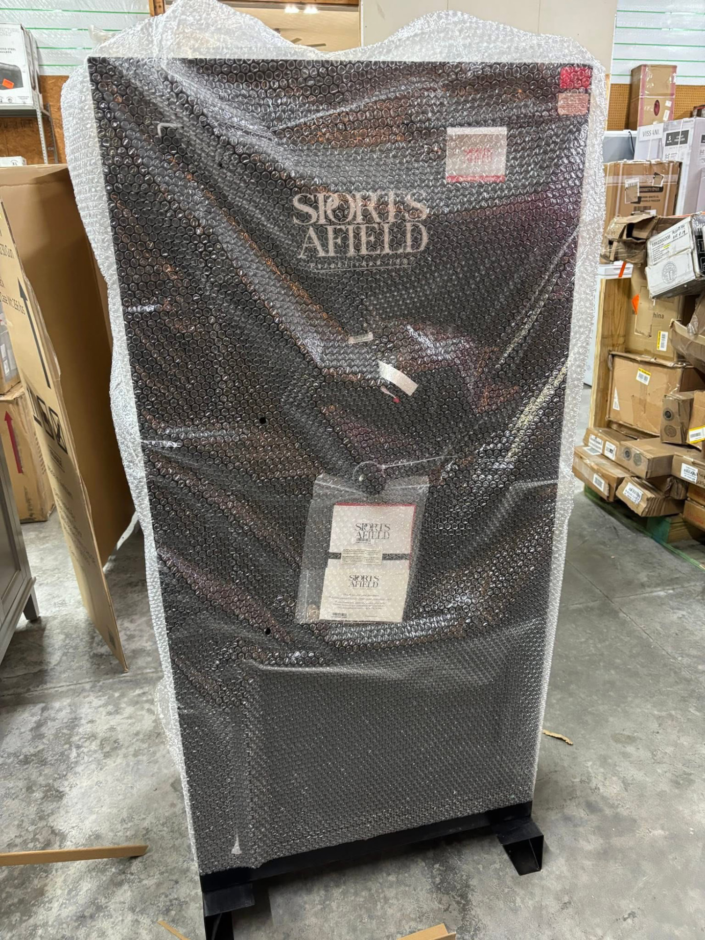 Large Sports Afield gun safe wrapped in bubble wrap on the warehouse floor