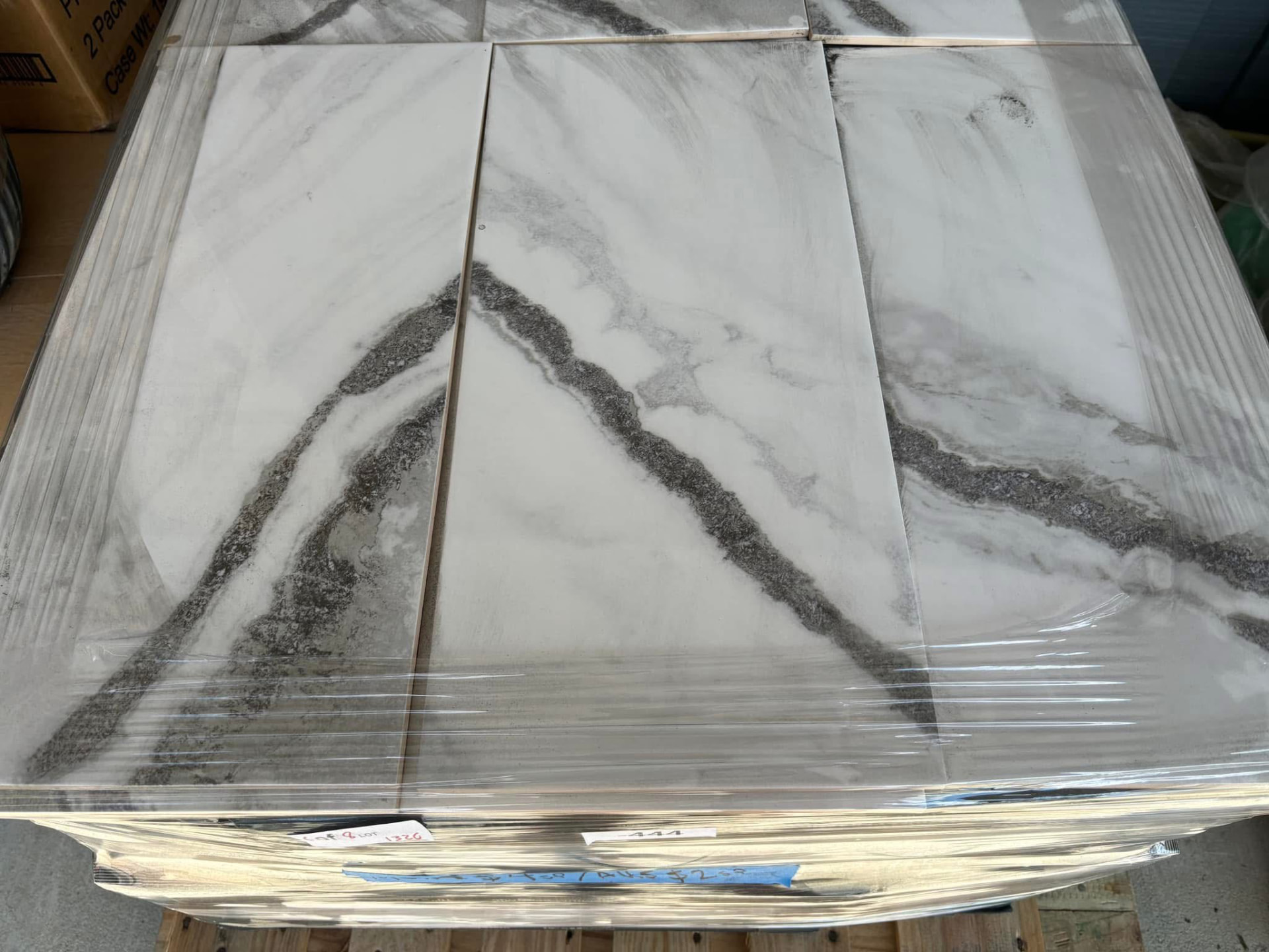 Shrink-wrapped pallet of large white marble-look porcelain tile with grey veining