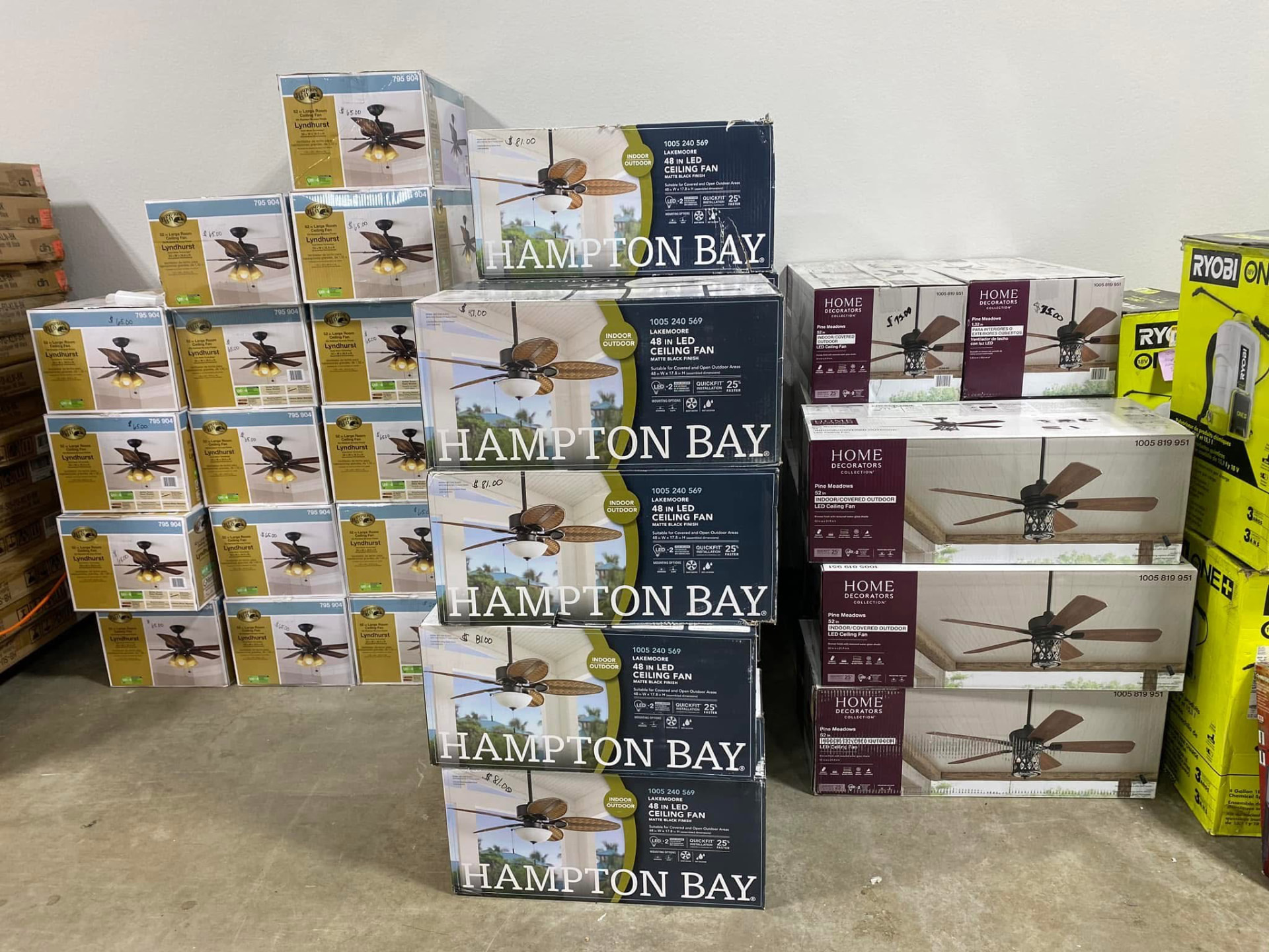 Stacks of boxed Hampton Bay and Home Decorators Collection LED ceiling fans in the warehouse